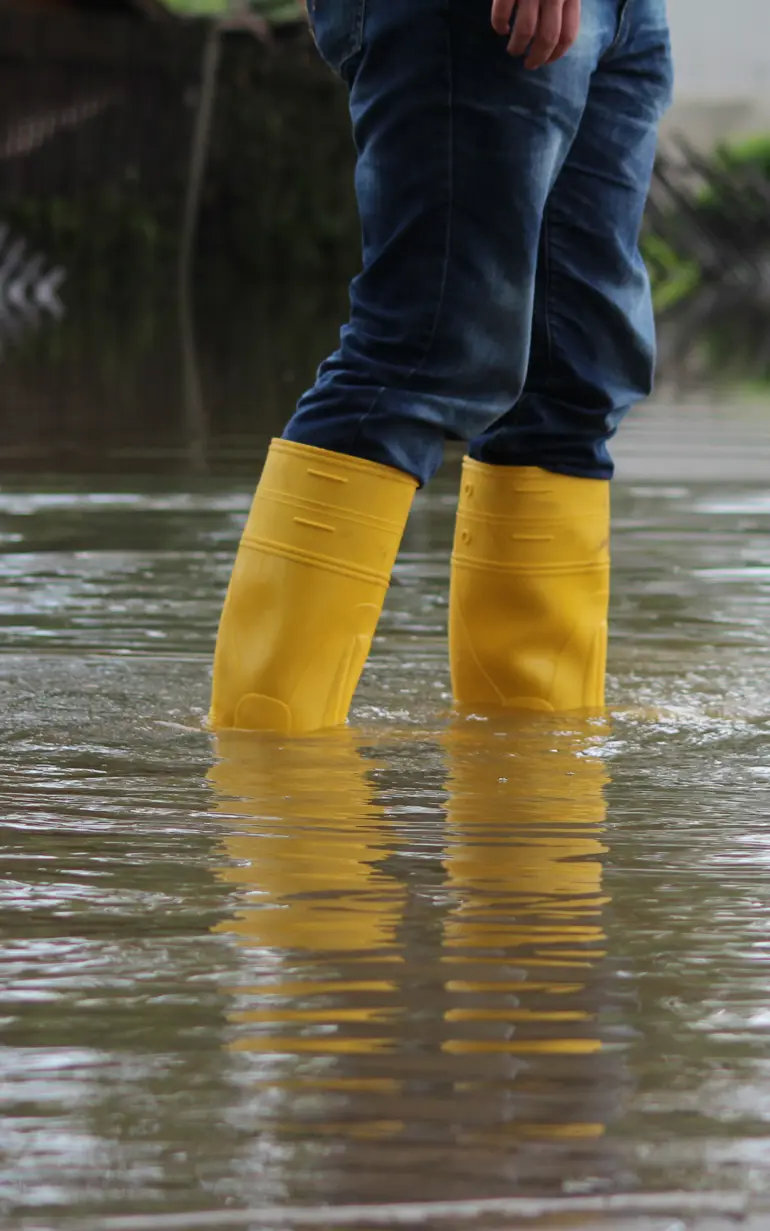 Ben med gummistövlar i vatten
