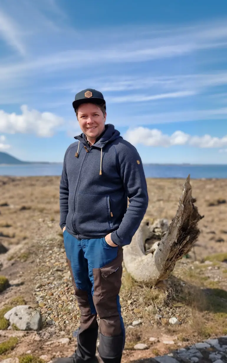 Man på stenlagd mark med hav i bakgrund