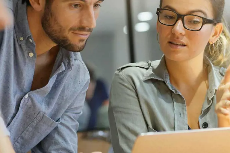 Two people reviewing data on a laptop